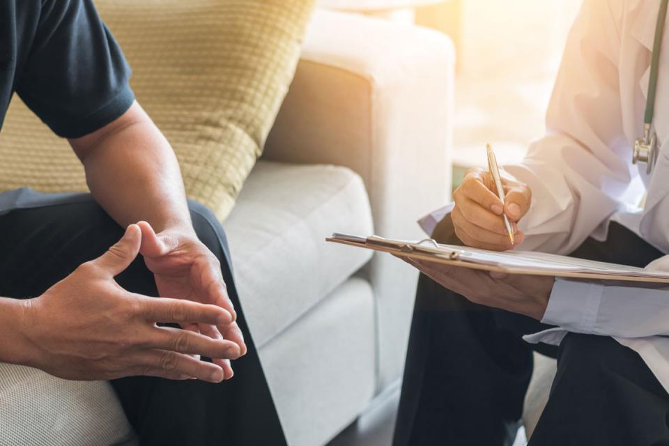 Doctor taking notes on a chart with a male patient