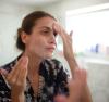 Young woman washing her face in the mirror