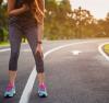 Young woman jogger bent over trying to catch her breath