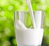 Milk being poured into a glass with green tree background